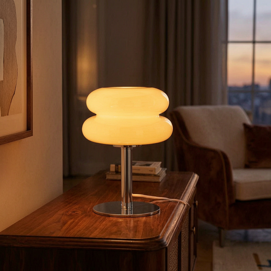 Lámpara de mesa de vidrio de diseño italiano encendida sobre un aparador