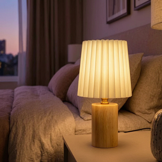 Lámpara de mesa plisada encendida en una mesita de noche
