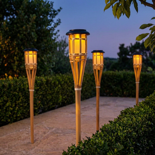 Antorchas solares de bambú encendidas en un jardín al atardecer